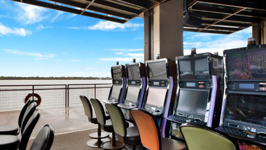 View past the slot machines to the the river from inside the Riverbend Gaming/Smoking Terrace at L'Auberge Casino